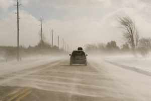 Vehicle driving on highway blowing snow