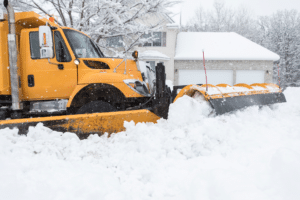 Snow plow pushing snow along residential area
