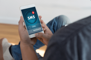 Person holding cell phone with SMS message displayed